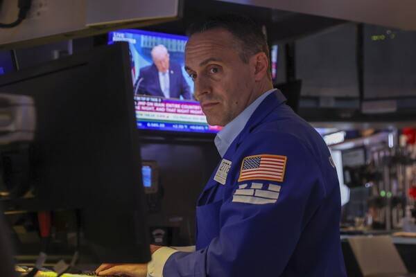 2026년 4월 6일, 미국 뉴욕주 뉴욕 증권거래소에서 한 거래자가 업무를 보고 있는 동안, 스크린에는 도널드 트럼프 미국 대통령이 이란 전쟁 관련 기자회견에서 연설하는 모습이 나오고 있다. [출처=연합뉴스]