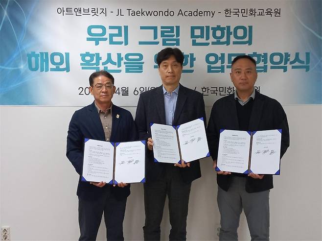 From left: Yang Jung-seok, CEO of Art and Bridge, Song Chang-soo, head of the Korea Institute of Folk Painting Education, and Yoon Byung-yun, master of JL Taekwondo Academy, pose during a signing ceremony Monday. (Art and Bridge)
