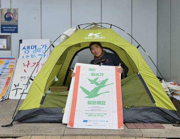 박중록 낙동강하구지키기전국시민행동 공동집행위원장이 9일 오전 창원시 성산구 신월동 낙동강유역환경청 정문 앞쪽에 설치한 텐트 안에서 손팻말을 들고 있다. 그는 지난달 26일부터 낙동강청 정문 앞에 3~4인용 텐트를 치고 농성에 들어갔다. /최석환 기자