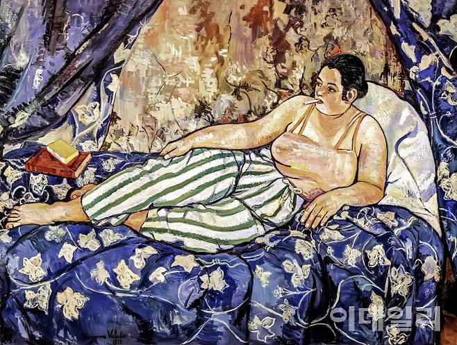 수잔 발라동의 ‘푸른 방’(1923). 침대에 비스듬하게 기댄 여인. 전통적으로 서양화에 자주 등장하는 여성 누드화의 포즈다. 하지만 그림 속 여인은 이제껏과는 전혀 다른 모습이다. 줄무늬 파자마 바지에 분홍 캐미솔을 입고 담배까지 물었다. 발치에 던져둔 책도 눈길을 끈다. 담배나 책은 당시 남성의 전유물로 여겨졌다. 화가에게 그림을 주문하고 그 그림을 즐겨온 남성의 시선을 빼버리는 것으로 발라동은 관습이 요구하는 여성성을 대놓고 거부했다. 후대 여성 예술가들에게 크게 영향을 미친 작품이다. 캔버스에 유채, 90×116㎝. 퐁피두센터 국립현대미술관(프랑스 파리) 소장.