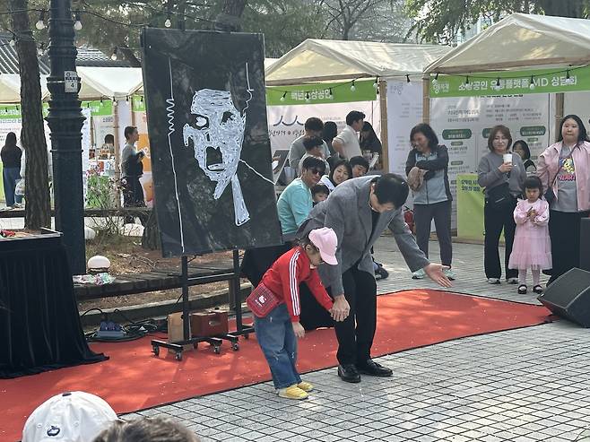 11일 ‘4월 동행축제’가 진행된 전북 전주시 전북대학교 알림의거리에서 행사 관계자가 시민과 마술 공연을 선보이고 있다.(서이원 기자 @iwonseo96)