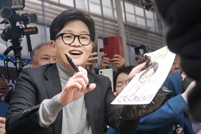 국민의힘 한동훈 전 대표가 지난달 22일 서울 동대문구 경동시장을 방문해 상인에게 사인해주고 있다. [연합뉴스 자료사진]