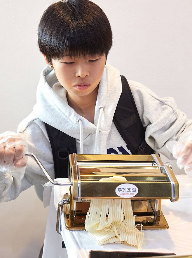 반죽을 밀대로 펴준 다음 제면기에 넣고 직접 면을 뽑아보는 제면 체험을 하고 있는 곽준혁 학생기자.