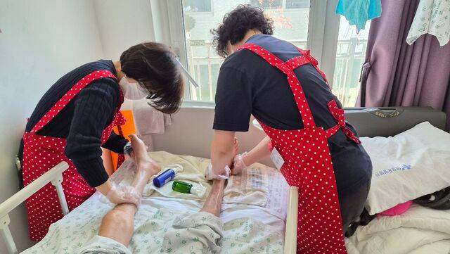 서울 송파구 주님의교회 봉사자들이 지난해 7월 경기도 용인의 한 호스피스병동에서 환자의 발을 씻긴 뒤 로션으로 마사지하고 있다. 교회 제공