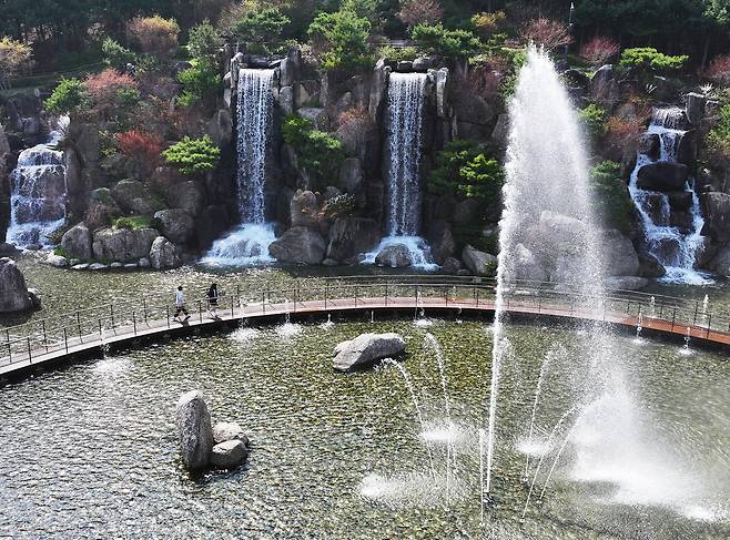 때 이른 초여름 날씨를 보인 13일 경기도 안산시 노적봉 폭포공원을 찾은 시민들이 시원하게 쏟아지는 폭포수를 바라보고 있다. [연합]