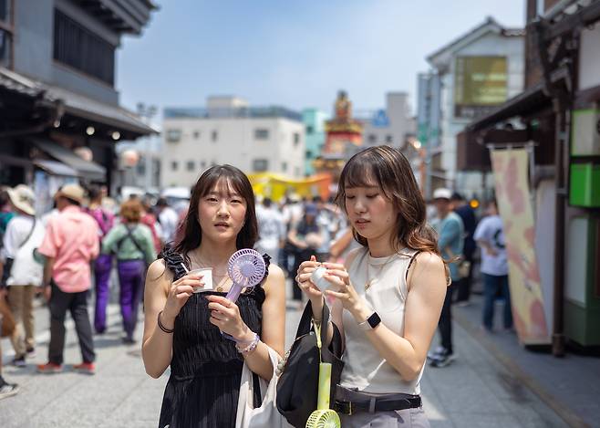 일본의 한 여름 축제를 찾은 관광객이 휴대용 선풍기를 사용하고 있다.[게티이미지뱅크]