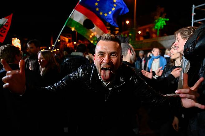 [부다페스트=AP/뉴시스] 12일(현지 시간) 헝가리 부다페스트 거리에서 총선 부분 개표 결과 발표를 접한 한 남성이 환호하고 있다. 헝가리 총선에서 야당인 티서당이 압도적으로 승리한 것으로 나타났다. 패배를 인정한 피데스당의 빅토르 오르반 현 총리는 16년 만에 총리직에서 물러나게 됐다. 2026.04.13.