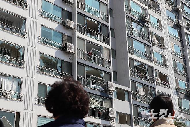 아파트 주민들이 폭발 사고로 피해를 입은 아파트를 바라보고 있다.