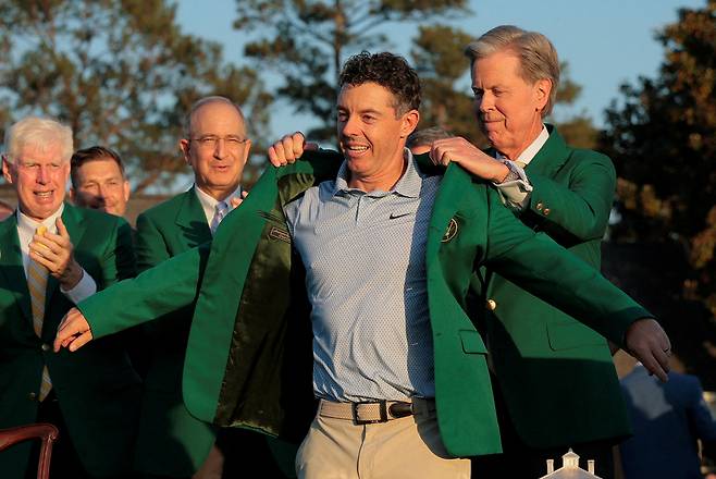 로리 매킬로이가 12일(현지 시간) 미국 조지아주 오거스타 내셔널GC에서 진행된 제90회 마스터스 시상식에서 프레드 리들리(오른쪽) 오거스타 내셔널GC 회장이 입혀주는 그린 재킷을 걸치고 있다. 그린 재킷은 전년도 우승자가 입혀주는 게 전통이지만 지난해 우승자도 매킬로이여서 리들리 회장이 나섰다. 로이터연합뉴스