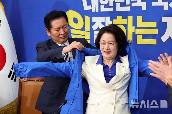 [서울=뉴시스] 김금보 기자 = 추미애 더불어민주당 경기도지사 후보가 13일 오전 서울 여의도 국회에서 열린 환영식에서 정청래 더불어민주당 대표로 부터 당 점퍼를 받아 입고 있다. 2026.04.13.kgb@newsis.com