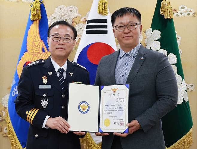 14일 오전 경기남부경찰청에서 열린 수여식에서 황창선 경기남부청장(왼쪽)이 대형 참사를 막은 시민 문도균 씨(오른쪽)에게 표창장을 전달한 뒤 기념 촬영을 하고 있다. 문씨는 기사가 숨져 통제 불능이 된 버스의 핸들을 잡고 손으로 브레이크를 눌러 승객 7명의 생명을 구한 공로를 인정받았다. 경기남부경찰청 제공