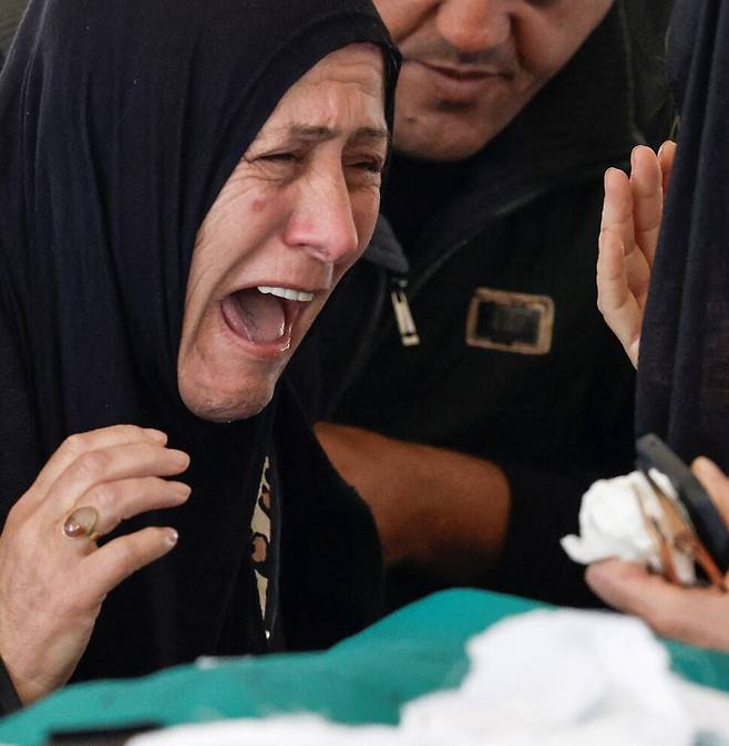 레바논 티르의 알카라브 모스크에서 12일(현지시각) 이스라엘의 공습으로 사망한 가족의 시신을 두고 유족이 오열하고 있다. 로이터=연합뉴스