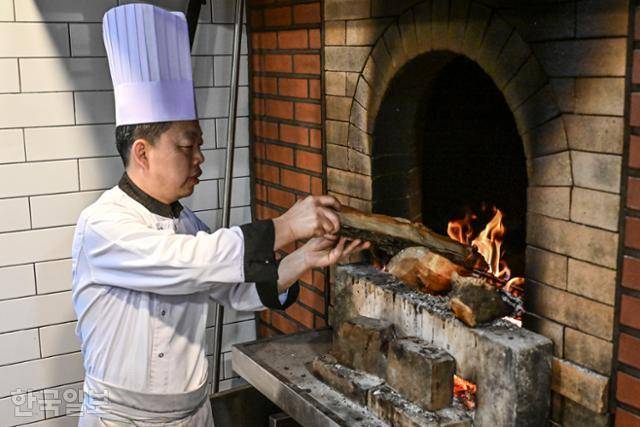 왕쉬안위안 셰프가 8일 서울 강남구 왕스덕 매장 주방에서 대추나무 장작을 화덕에 넣고 있다. 정다빈 기자