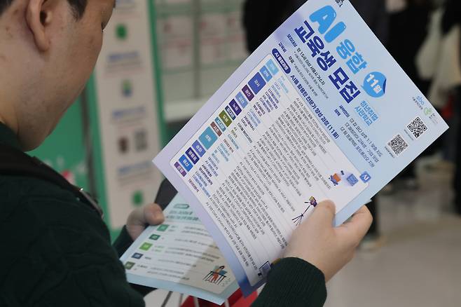 지난해 동대문디자인플라자(DDP)에서 열린 ‘서울시 일자리 박람회’에서 한 구직자가 AI 일자리 교육 관련 홍보물을 살펴보고 있다. [연합]