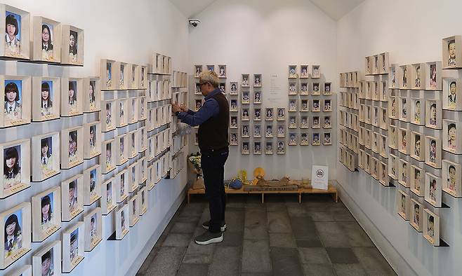 세월호 참사 12주기를 앞둔 15일 서울 중구 서울시의회 앞 세월호 기억공간인 ‘기억과 빛’에서 한 남성이 세월호 희생자 사진이 담긴 액자를 청소하고 있다. 이재문 기자