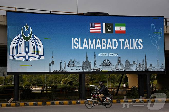 파키스탄 이슬라마바드에서 한 남성이 도로변에 설치된 광고판 앞을 오토바이를 타고 지나가고 있다. 2026.4.10 ⓒ 로이터=뉴스1