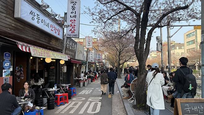 Crowds line the sidewalk along a road above Seongbuk Stream in central Seoul on April 11. [WOO JI-WON]