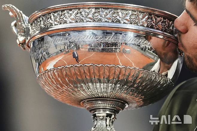 [파리=AP/뉴시스] 카를로스 알카라스(2위·스페인)가 8일(현지 시간) 프랑스 파리 롤랑가로스에서 열린 프랑스오픈 남자 단식 정상에 올라 트로피를 들고 입 맞추고 있다. 알카라스는 결승전에서 얀니크 신네르(1위·이탈리아)와 5시간 29분 대접전 끝에 3-2(4-6 6-7 6-4 7-6 7-6) 역전승을 거두고 대회 2연패를 달성했다. 2025.06.09.