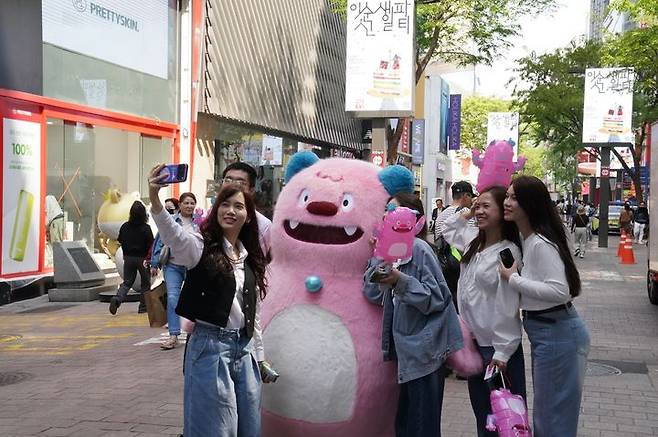 [서울=뉴시스] 외국인 관광객들이 명동 거리 일대에서 해치와 사진촬영을 하고 있는 모습. (사진=롯데면세점 제공)  *재판매 및 DB 금지