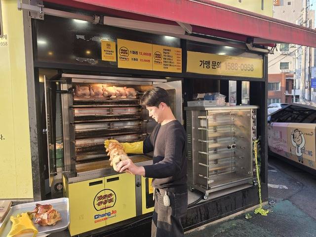 김종진 대표가 운영 중인 창조통닭 오븐 기계에서 한 가맹점주가 조리된 통닭을 꺼내고 있다. 권영진 기자