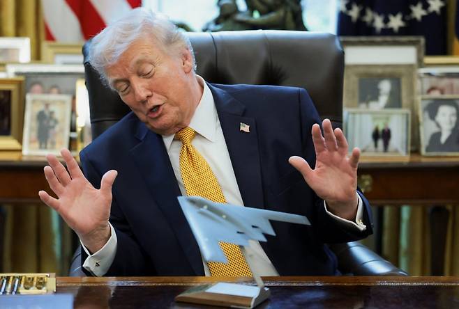 도널드 트럼프 미국 대통령이 지난 3월 16일 백악관 책상에 놓인 B-2 스텔스 폭격기 모형을 바라보며 두 손을 들어 보이고 있다. 로이터연합뉴스