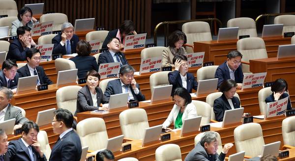 18일 국회에서 열린 4월 임시국회 제6차 본회의 시작을 기다리는 조국혁신당 서왕진 원내대표 등 의원들의 자리에 더불어민주당과 국민의힘이 합의한 공직선거법 개정안, 정당법 개정안 등을 비판하는 유인물이 붙어 있다. /연합뉴스
