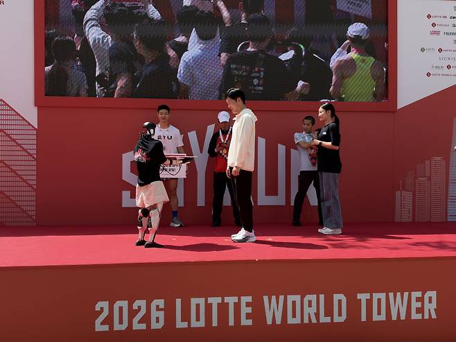 19일 서울 잠실에서 열린 ‘2026 롯데월드타워 스카이런(SKY RUN)’ 엘리트부문 시상자로 오른 롯데이노베이트 휴머노이드로봇(왼쪽). 사진=황민주 기자