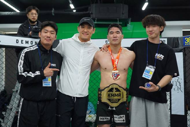 KMMA 슈퍼라이트급 챔피언에 오른 류정현(가운데 오른쪽)이 소속팀 양산팀매드 지도자 ‘쌍칼’ 유상훈(가운데 왼쪽)과 함께 기념 사진을 촬영 중이다. 사진제공 = 뽀빠이연합의원KMMA파이터에이전시