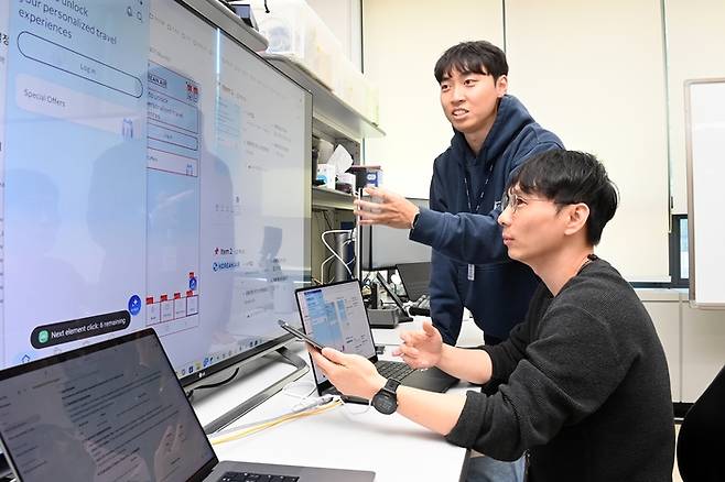 ETRI 연구진이 AI 기반 UI·UX 접근성 자동 점검 기술 시연 화면을 보며 기능 구현을 논의하는 모습. <사진=ETRI>