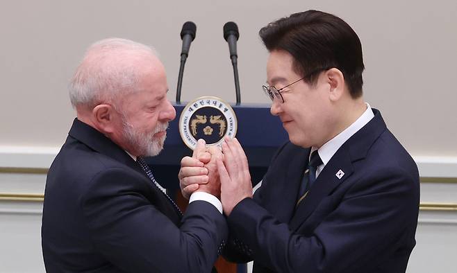 이재명 대통령이 지난 2월 23일 청와대에서 열린 루이스 이나시우 룰라 다시우바 브라질 대통령 국빈 방한 환영 만찬에서 답사를 위해 이동하는 룰라 대통령과 손을 맞잡고 있다. 연합뉴스