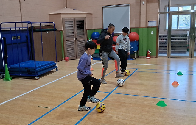 ▲ 의성군 옥전초등학교 체육관에서 학생들이 원어민 강사의 지도에 따라 공을 다루며 영어축구교실 활동에 참여하고 있다. 경상북도 의성교육지원청 제공