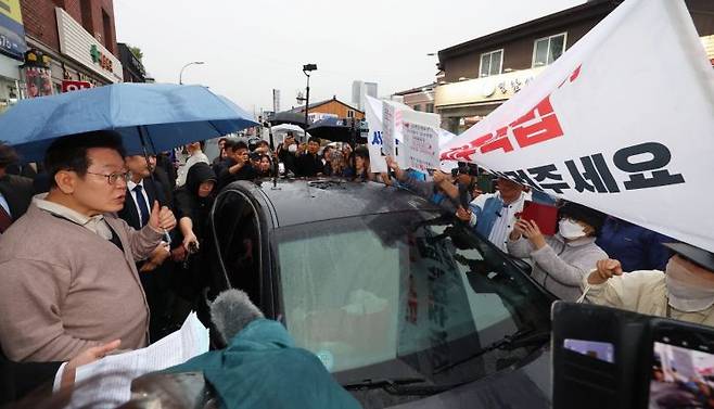 지난해 5월 이재명 당시 민주당 대선후보가 경북 고령군에서 대구 시민의 지역주택조합 관련 하소연을 듣고 있다. 연합뉴스