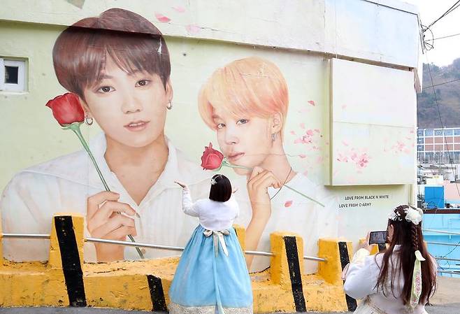 부산 서구 감천문화마을에서 외국인 관광객들이 부산이 고향인 BTS 멤버 정국·지민이 그려진 대형 벽화를 배경으로 기념촬영을 하고 있다. 뉴스1