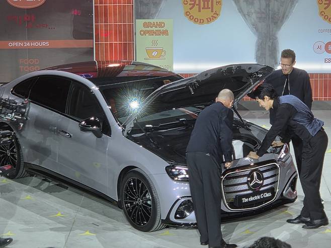 Chief Technology Officer Jorg Berzer, bottom left, pulls out a bag out of the trunk of the all-new electric C-Class for actor Park Jae-min, bottom right, during the vehicle's world premiere event held at pop-up venue XYZ Seoul in Seongdong District, eastern Seoul, on April 20. [KIM MIN-YOUNG]