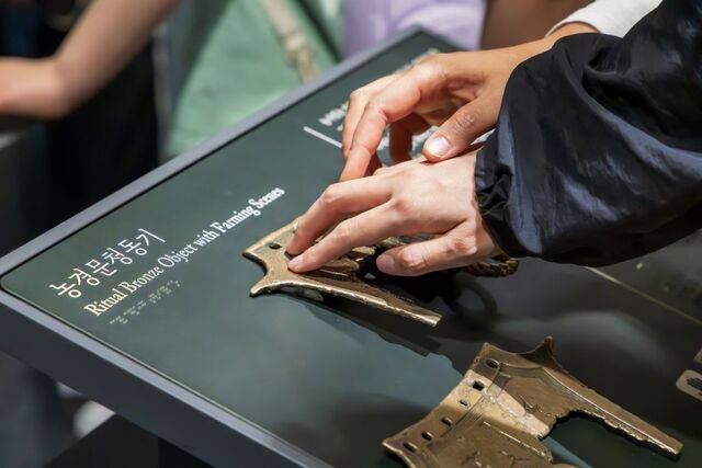 현장영상해설 프로그램에 동행한 기자가 지난 18일 서울 용산구 국립중앙박물관 선사고대관에서 해설사의 도움을 받아 촉각전시품 ‘농경문청동기’를 매만지고 있다. 서울관광재단 제공