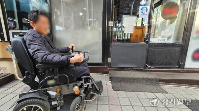 오현태씨가 휠체어를 탄 채 인천 남동구 한 우수음식점으로 들어서려 하지만 문턱에 걸려 들어가지 못하고 난처해 하고 있다. 박기웅 기자