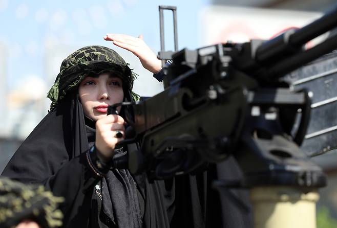 17일(현지시간) 이란 테헤란 시내에서 열린 반미·반이스라엘 시위에서 군용차량에 탑승한 채 기관포를 붙들고 있는 이란 여성. EPA연합뉴스