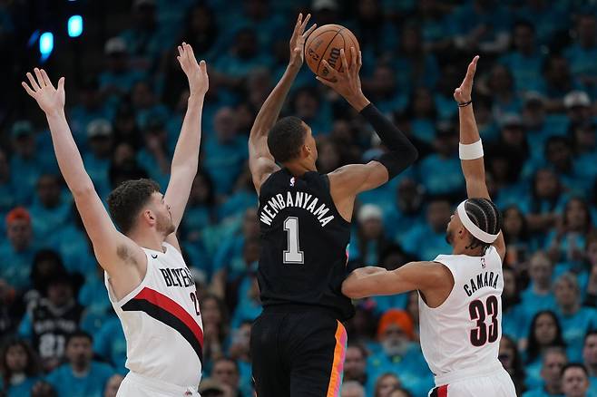 샌안토니오 빅토르 웸반야마(가운데)가 20일(한국시간) 프로스트뱅크 센터서 열린 포틀랜드와 NBA&nbsp;PO 1라운드 1차전 도중  도노반 클링언(왼쪽)과 투마니 카라마  사이에서 슛을 던지고 있다. 샌안토니오｜AP뉴시스