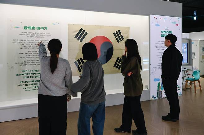 국립인천해양박물관을 찾은 관람객들이 대한제국의 첫 근대식 기선인 ‘광제호’에 게양됐던 태극기를 살펴보고 있다. 국립인천해양박물관 제공