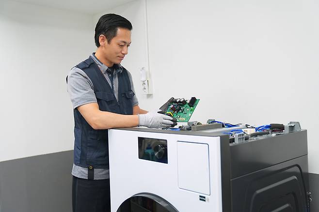 삼성전자서비스 엔지니어가 세탁기를 수리하고 있다.[삼성전자서비스]