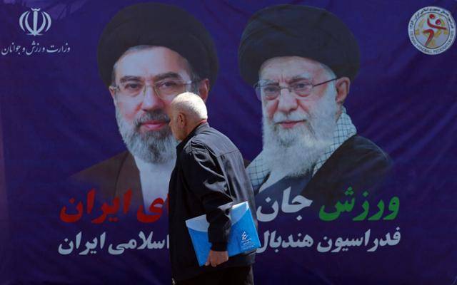 한 남성이 15일 이란 테헤란의 한 길가에 내걸린 모즈타파 하메네이 이란 최고지도자와 아야톨라 세예드 알리 하메네이 이란 전 최고지도자 사진 앞을 걸어가고 있다. 테헤란=AFP 연합뉴스