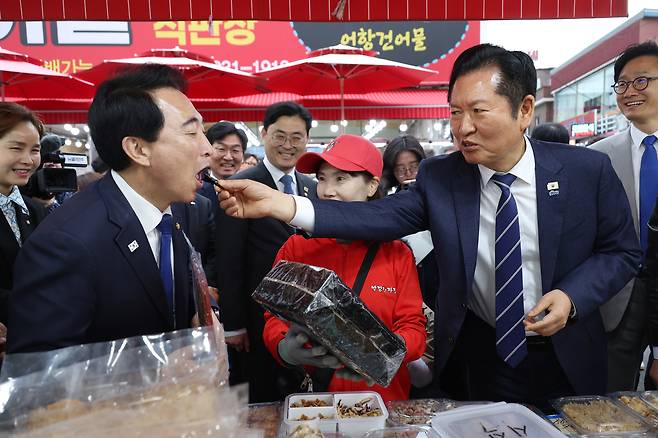 정청래 더불어민주당 대표가 지난 20일 충남 보령시 대천항수산시장을 방문해 박수현 충남도지사 후보에게 돌김을 먹여주고 있다. 연합뉴스