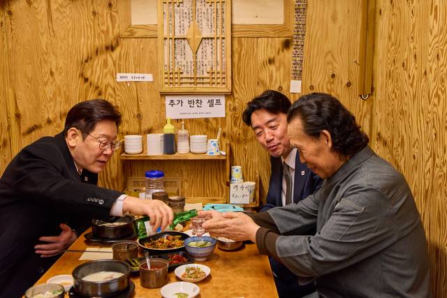 이재명 대통령이 서울 종로구 통인시장 한식당에서 강훈식 대통령비서실장과 저녁 식사를 하며 식당 주인에게 술을 권하고 있다. 청와대 제공