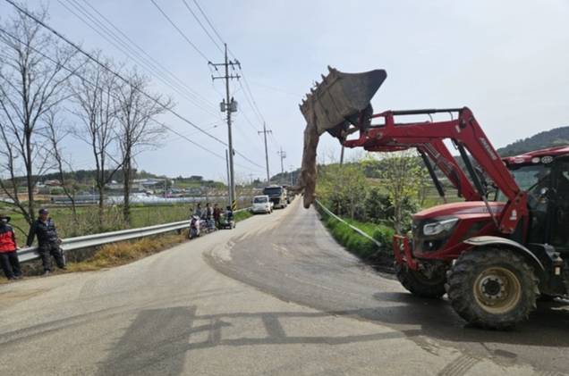 고창군 해리면 광승마을에서 축산 농가가 피해를 호소하며 죽은 송아지를 트랙터에 매단 채 시위를 벌이고 있는 가운데, 현장 인근 도로에는 덤프 트럭 10여 대가 줄지어 주차돼 있다. /박현표 기자
