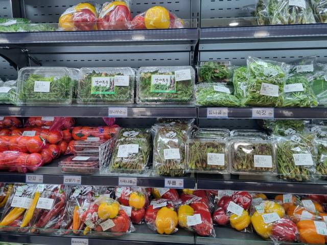 ‘다락’ 매대에 진열된 제철 봄나물과 파프리카. 품목마다 생산자 이름이 적힌 QR코드 가격표가 붙어 있다.