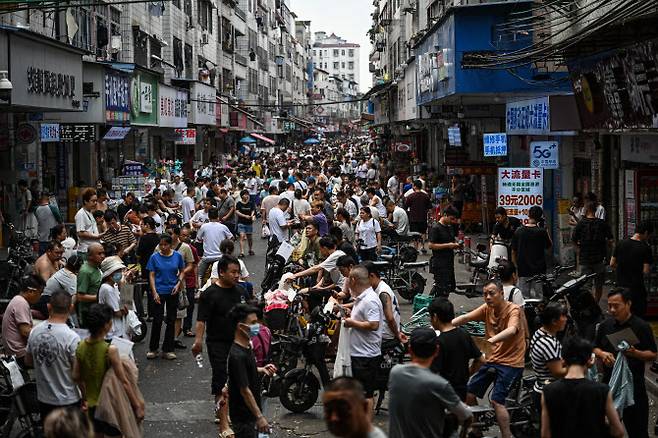 16일(현지시간) 중국 남부 광둥성 광저우의 한 도시 거리에서 의류 공장의 채용 담당자와 구직 노동자들이 대화를 나누고 있다. (사진=AFP)