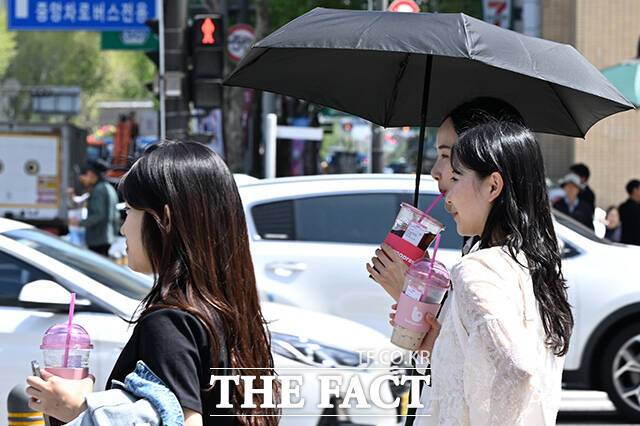 지난 16일 오후 서울 종로구 세종대로 일대에서 시민들이 양산을 쓰고 음료를 든 채 걸어가고 있다. /김성렬 기자