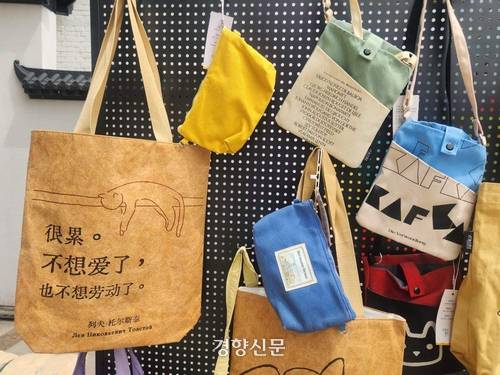 22일 원명원에서 열린 2026 베이징도서전에 참가한 한 서점이 마련한 천 가방 판매대. 가장 왼쪽 가방에는 ‘피곤해. 사랑도 노동도 하고 싶지 않아’라고 적혀 있다.