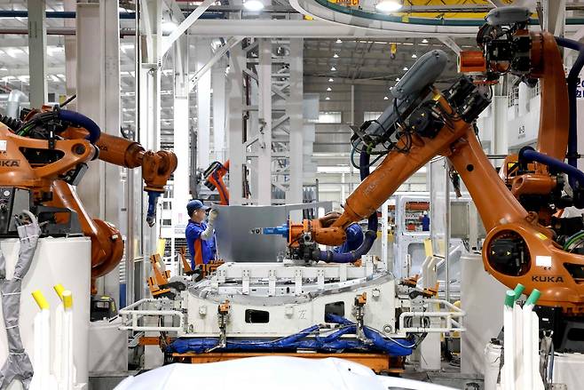 중국 동부 푸젠성 푸저우의 한 금형 및 스탬핑 회사 생산 작업장에서 작업자와 로봇 팔이 자동차 차체용 판금 부품을 생산하고 있다. [AFP]