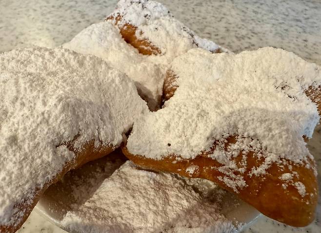 ‘카페 뒤 몽드(Café du Monde)’의 베녜(Beignet). 가운데 구멍이 없는 사각형의 프랑스식 도넛으로 프랑스인들은 “눈 덮인 알프스 못지않게 나를 흥분시키는 풍경이다”라고 표현한다. /박진배 뉴욕 FIT 교수·마이애미대학교 명예석좌교수
